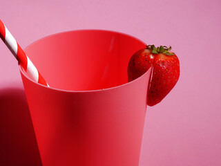 Pink beaker with strawberry and drinking straw 