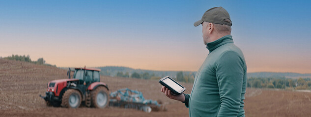 Portrait of 50s Caucasian male farmer using a tablet while standing in the field. Cloud technology...