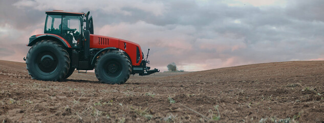 Tractor is driving through the field early in the morning. Shot with 2x anamorphic lens