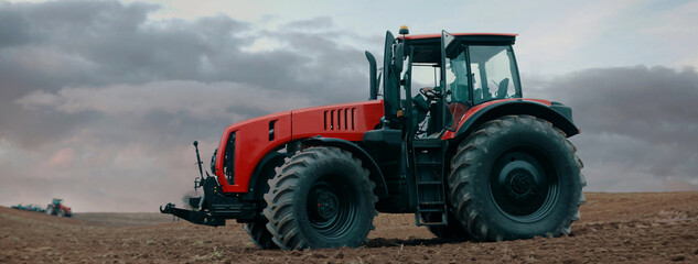 Tractor is driving through the field early in the morning. Shot with 2x anamorphic lens