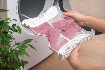 A man holds a dirty dryer filter. A man collects lint, hair, wool from the filter of a drying...