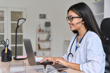 Side view on young asian doctor communicating online with patient on laptop