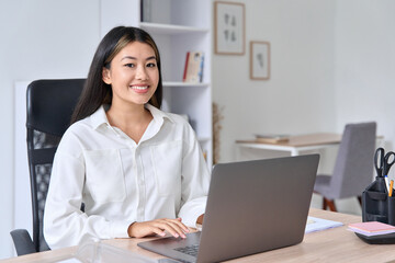 Portrait of smiling business asian woman freelancer portrait at desk with laptop