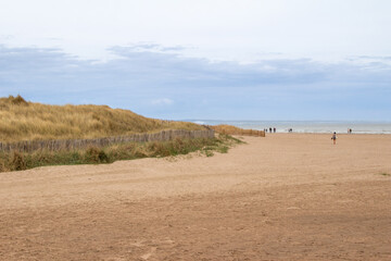 Fototapeta na wymiar Landscape view of a sandy beach along the North Sea on the east coast of Scotland, next to St. Andrews, with unidentifiable people.