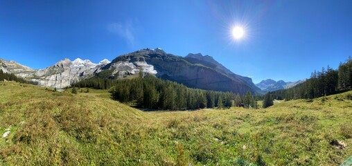 Mountains landscape on the summer day with blue sky. Switzerland mountain with rocks, trees and forest. Nature landscape view with mountains and lake. Lake in the mountains. 