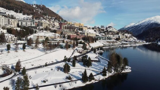 St Moritz, Switzerland: Aerial drone footage of the Saint Moritz ski resort village and lake on a sunny winter day in the Engadine valley in Canton Graubunden in the Swiss alps. 