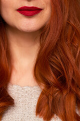 A picture of a red, wavy haired woman’s chin and bust 