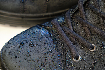 close-up details waterproof men's black boots. Drops of rain on suede shoes.