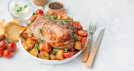 Baked turkey breast with baked potatoes, greens and fresh cherry tomatoes on a light background. Side view. Copy space.