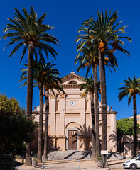 Palm trees in front of the mercy church (Eglise de la Misericorde) in the center of L'Ile-Rousse,...