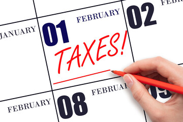 Hand drawing red line and writing the text Taxes on calendar date February 1. Remind date of tax payment