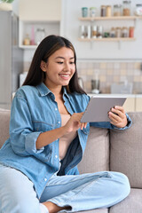 Young casual asian woman entrepreneur using digital tablet relaxing at home