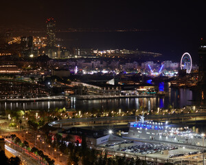 Vista de una ciudad de noche con todo su esplendor y una feria con una noria al fondo.