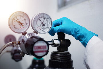 Closeup of a scientist's hand, checking gas from pressure gauge for a laboratory chromatography...