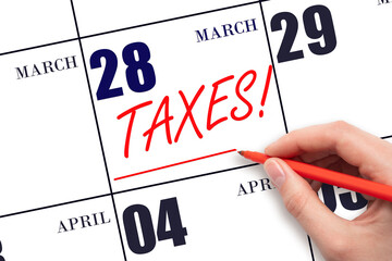 Hand drawing red line and writing the text Taxes on calendar date March 28. Remind date of tax payment