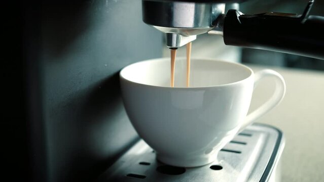 Flowing fresh ground coffee. Home making hot Espresso.Concept Drinking roasted black coffee in the morning.Pouring coffee stream from machine in cup. Pouring coffee stream from machine in cup