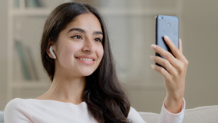 Beautiful arabian middle eastern girl teen wears wireless headphones talking at mobile camera...