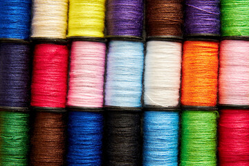 Background pattern of set of colorful rainbow sew thread spools on the wooden tailor table. Embroidery background