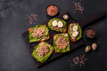 Delicious fresh sandwiches with toast, canned salmon, salad and quail eggs