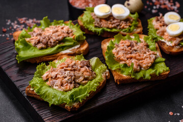 Delicious fresh sandwiches with toast, canned salmon, salad and quail eggs