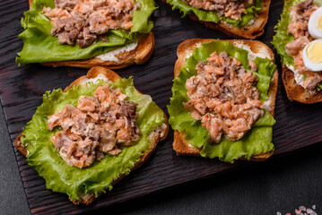 Delicious fresh sandwiches with toast, canned salmon, salad and quail eggs