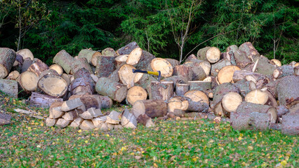 Old ax and a deck for chopping wood. Dry oak firewood stacked in a pile, chopped wood for winter heating of the fireplace. Natural wood background.