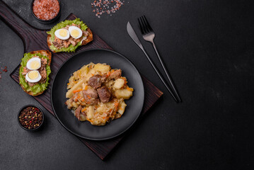 Delicious vegetable stew with beef, potatoes, carrots and cabbage in a black plate