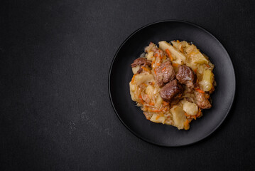 Delicious vegetable stew with beef, potatoes, carrots and cabbage in a black plate