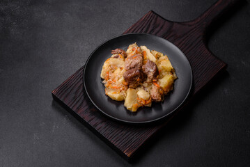 Delicious vegetable stew with beef, potatoes, carrots and cabbage in a black plate