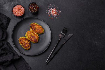 Diet vegetable cutlet from zucchini, carrot, herbs on a black plate
