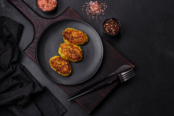 Diet vegetable cutlet from zucchini, carrot, herbs on a black plate