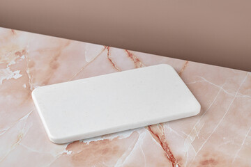 Empty blank white cutting board on beige pink marble background. Minimalist mock up for product...