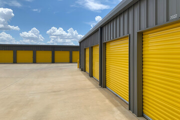 Outdoor shot of warehouses, storage facility, hangars or garages with yellow rolling gates - obrazy, fototapety, plakaty