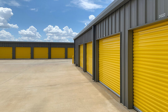 Outdoor shot of warehouses, storage facility, hangars or garages with yellow rolling gates