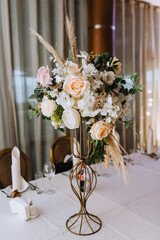 Flowers, reeds, wild flowers stand in a metal vase on a table in a restaurant, as a decoration. wedding photography.