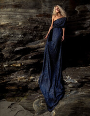 Beautiful blonde dress girl posing on beach. Long curly hair and stylish dress.