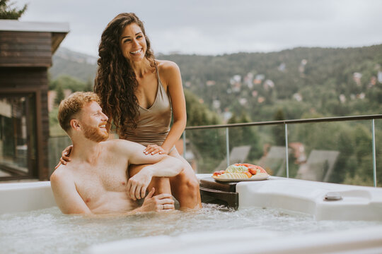 Young couple enjoying in outdoor hot tub on vacation