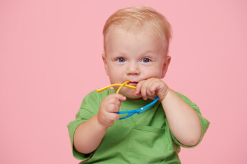 Portrait of male baby boy on pink background wearing glasses and looking at the camera. Smart baby...