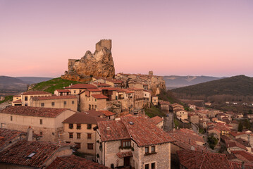 Panoramic landscape of the medieval village of Frías with old stone buildings and castle in the tophill at sunset, Burgos, Castile and Leon, Spain - obrazy, fototapety, plakaty
