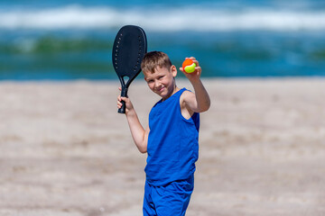 Young boy playing tennis on beach. Kids sport concept. Horizontal sport theme poster, greeting...