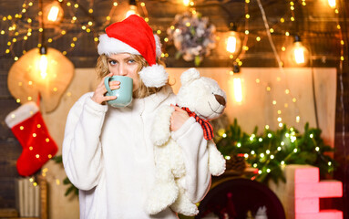 Fototapeta na wymiar hot and comfortable. Cheerful woman in sweater. winter holidays celebration. happy new year. christmas preparation. xmas mood. Woman toy bear present. girl in santa hat drink tea. coffee time