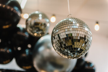 Disco ball. Happy New Year 2023. Bright glowing disco ball on photo booth with decor bulbs. Light...