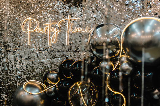 A place for congratulations for birthday. Arch or photo booth decorated black and silver balloons and led strips. Zone with decor sparkling sequins for wedding. Text party time. Happy New Year 2023.