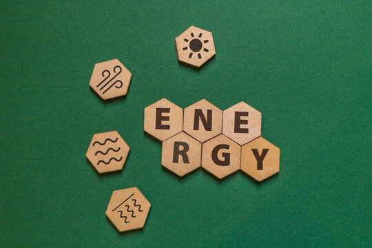 hexagonal wooden plates with the word energy and icons for solar, wind, hydro and geothermal energy on a green background