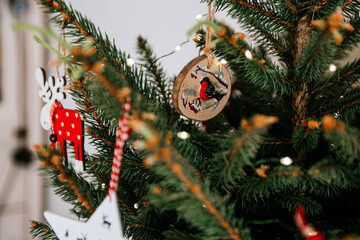Christmas tree with different wooden decorations. Christmas garland and Christmas lights. White and red colors. Christmas deer, star, snowflake, Bullfinch