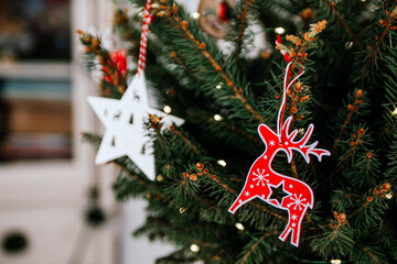 Christmas tree with different wooden decorations. Christmas garland and Christmas lights. White and red colors. Christmas deer, star, snowflake, Bullfinch