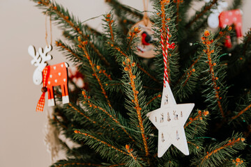 Christmas tree with different wooden decorations. Christmas garland and Christmas lights. White and red colors. Christmas deer, star, snowflake, Bullfinch