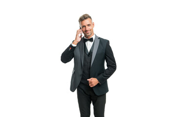 smiling positive businessman in tuxedo speak on phone isolated on white background