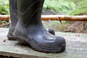 Robust rubber boots for your outdoor adventure. A man crosses a rickety wooden footbridge over a...