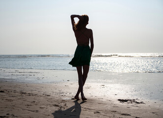 Mädchen im Kleid steht am Strand